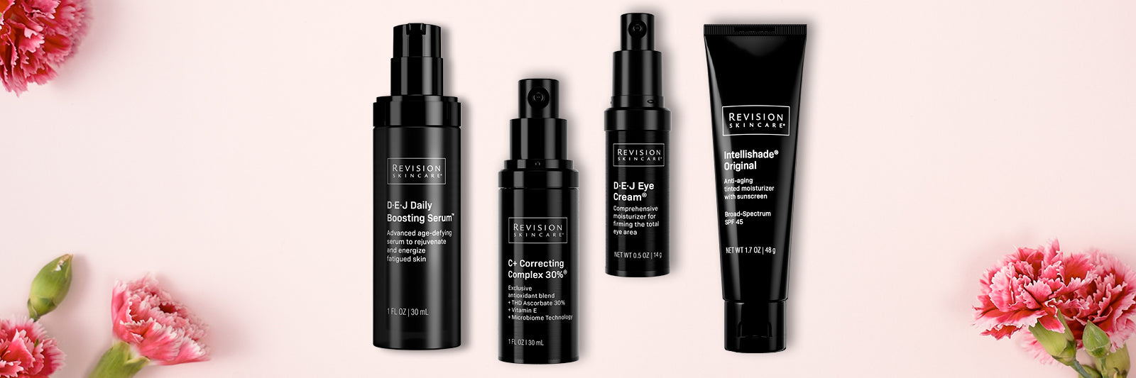 Four black bottles and tubes of Revision Skincare products are arranged in a row on a light pink background, surrounded by pink flowers at the corners.