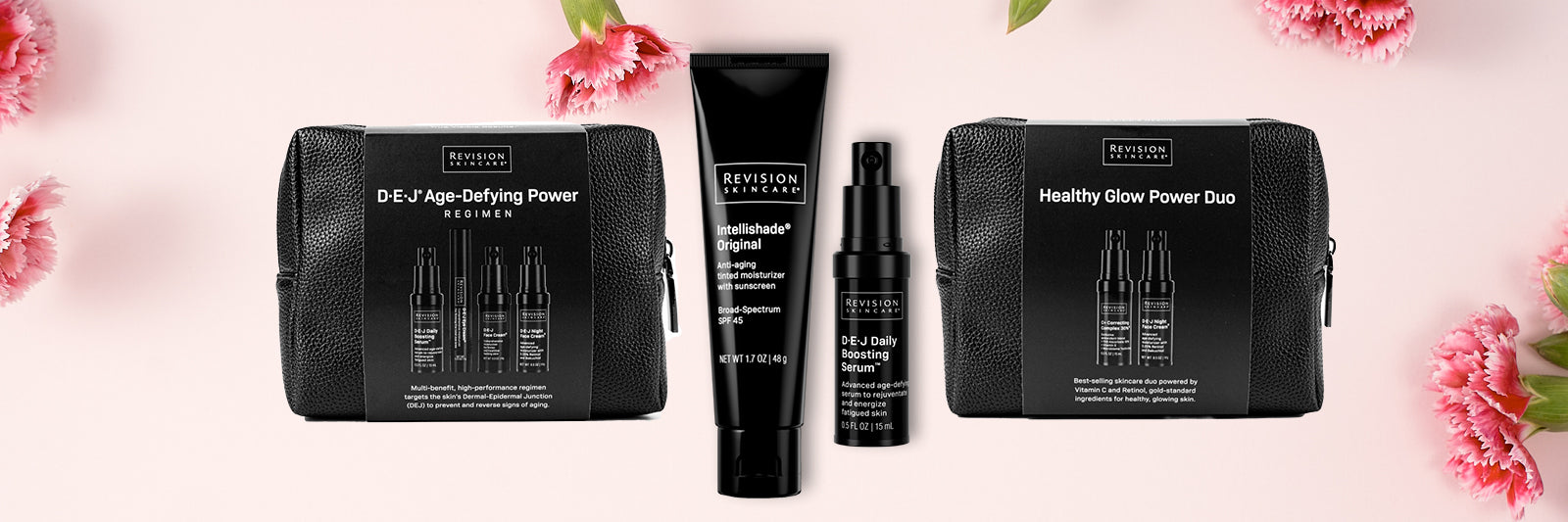Two black skincare sets and two bottles from Revision Skincare are displayed on a pink background with scattered pink flowers. The sets are labeled D·E·J Age-Defying Power and Healthy Glow Power Duo.
