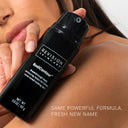 A person holds a black bottle of Revision Skincare BodiContour™ against bare skin. Text on the image: Same powerful formula, fresh new name.