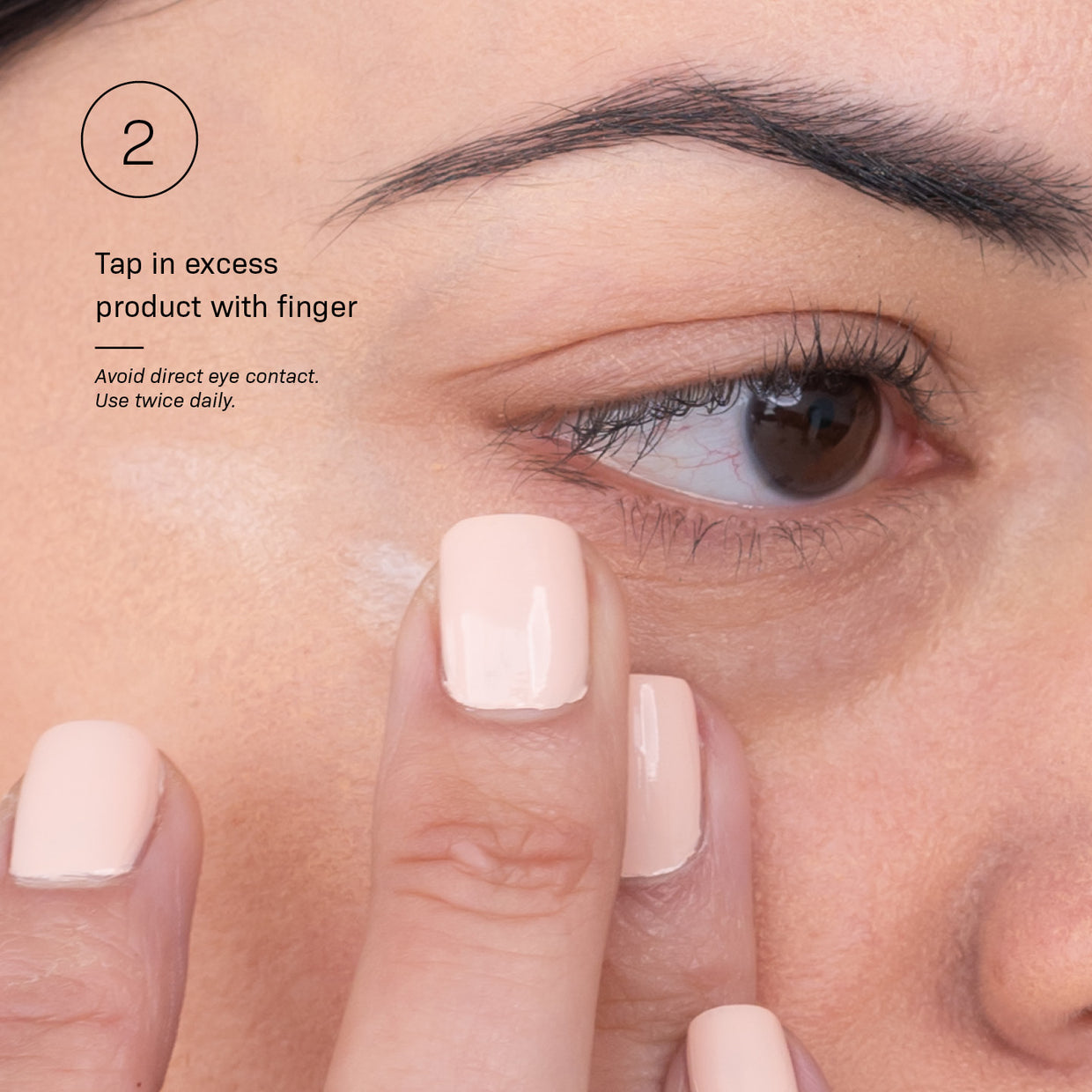 A close-up of a person gently tapping Revision Skincare’s C+ Brightening Eye Complex™ under their eye. On-screen text: “Tap in excess with finger. Avoid direct eye contact. Use twice daily to help reduce dark circles.”.