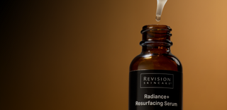 A dropper dispenses liquid into an open brown bottle labeled Revision Skincare Radiance+ Resurfacing Serum against a gradient brown background.