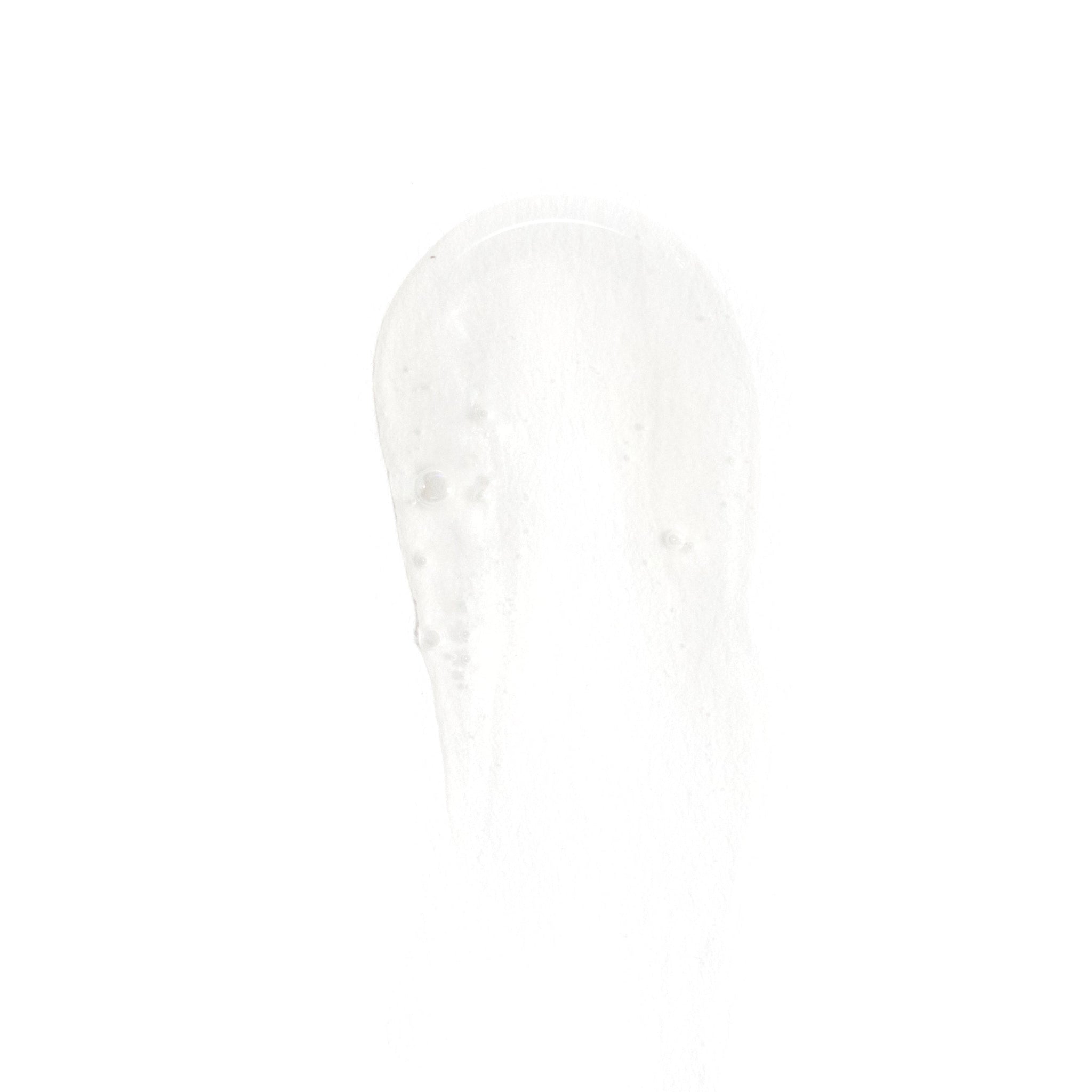 A small, clear drop of Revision Skincare Brightening Facial Wash gel is smeared on a white background, revealing its smooth, translucent texture with tiny bubbles inside.