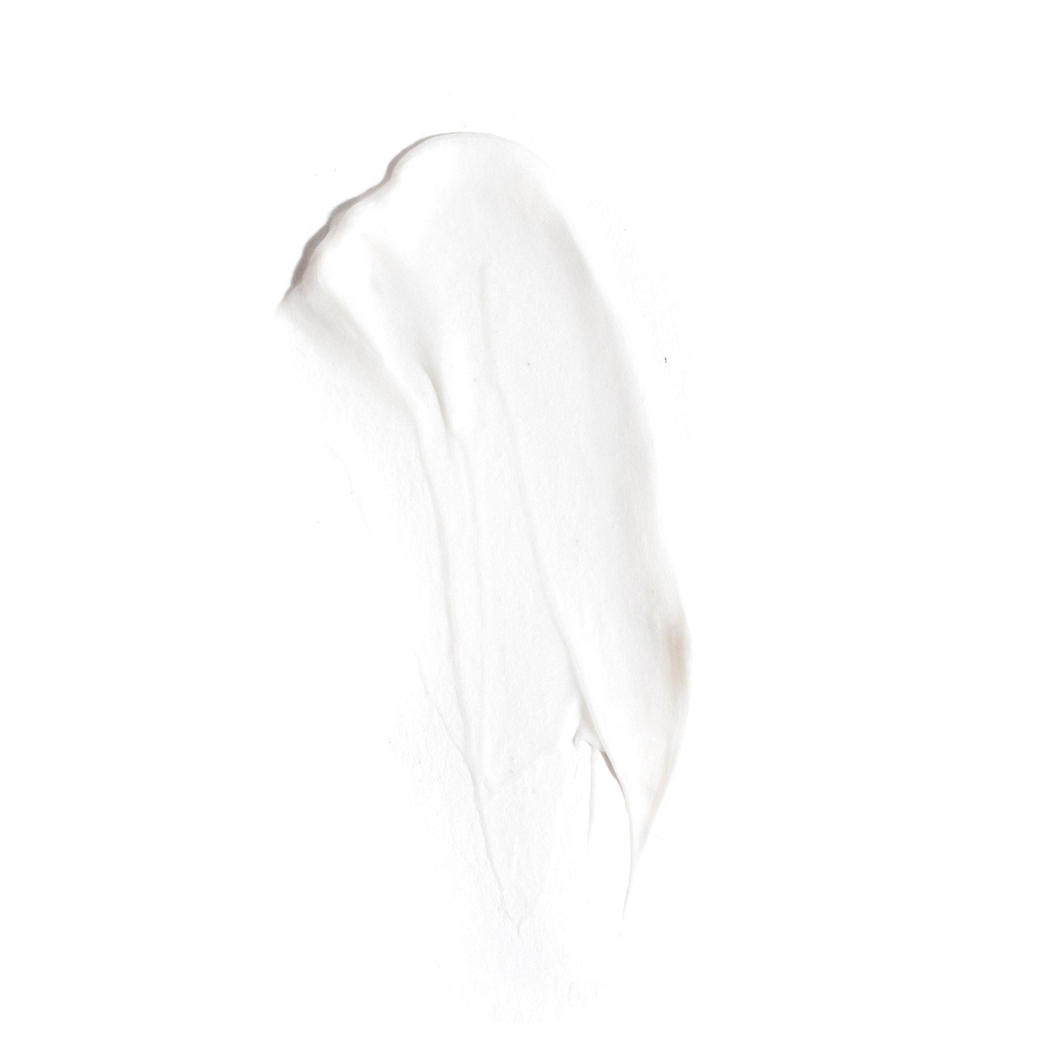A smear of creamy white lotion on a plain background highlights the smooth texture of Revision Skincare D·E·J Face Cream®, ideal for visually representing its skin-renewing, texture-improving benefits.
