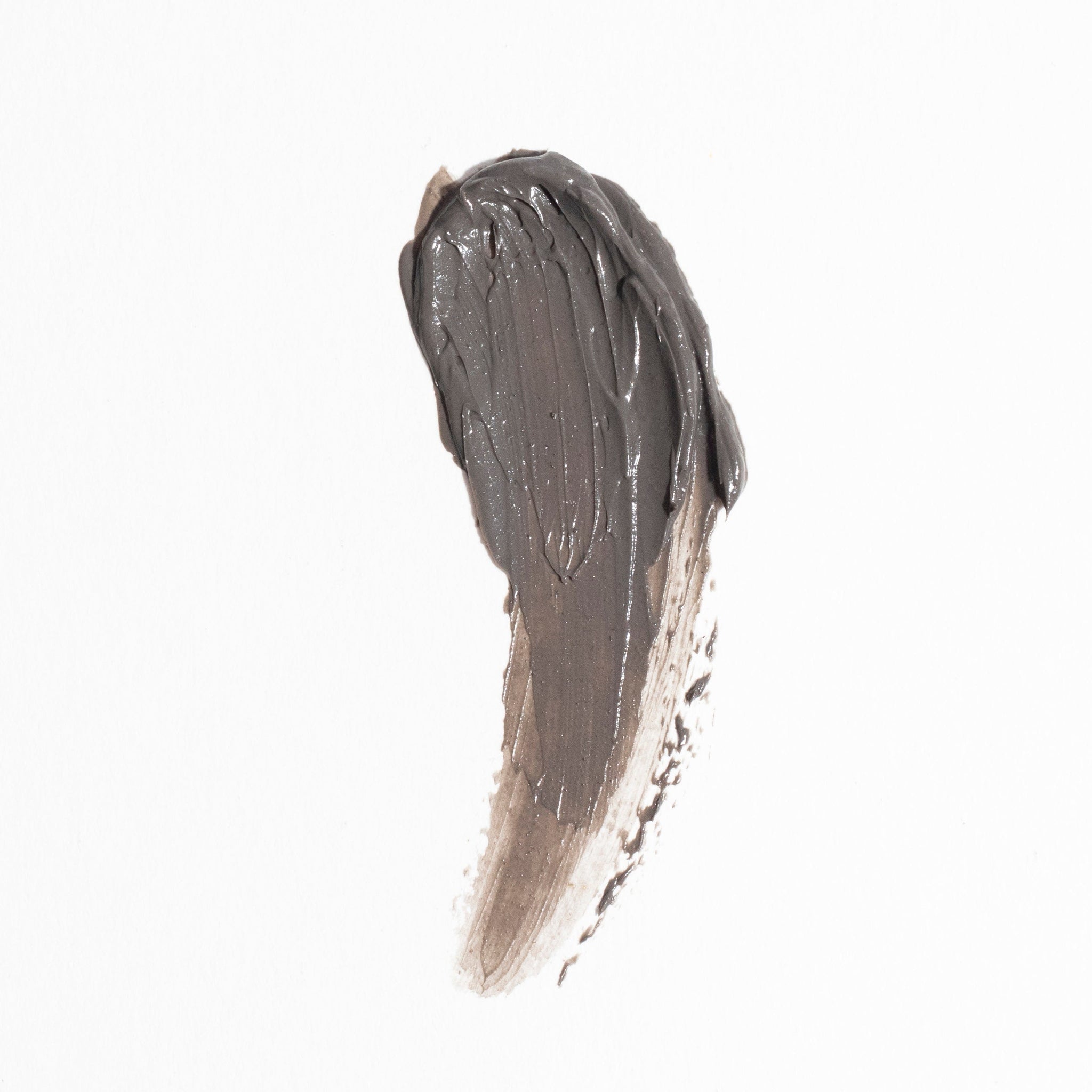 A thick, dark gray brushstroke of Revision Skincare Pore Purifying Clay Mask is smeared on a white background, resembling a paint swatch.