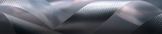 A close-up of a silvery, textured ribbon with a reflective, metallic surface, twisting and curling against a soft, blurred background in shades of gray and silver.