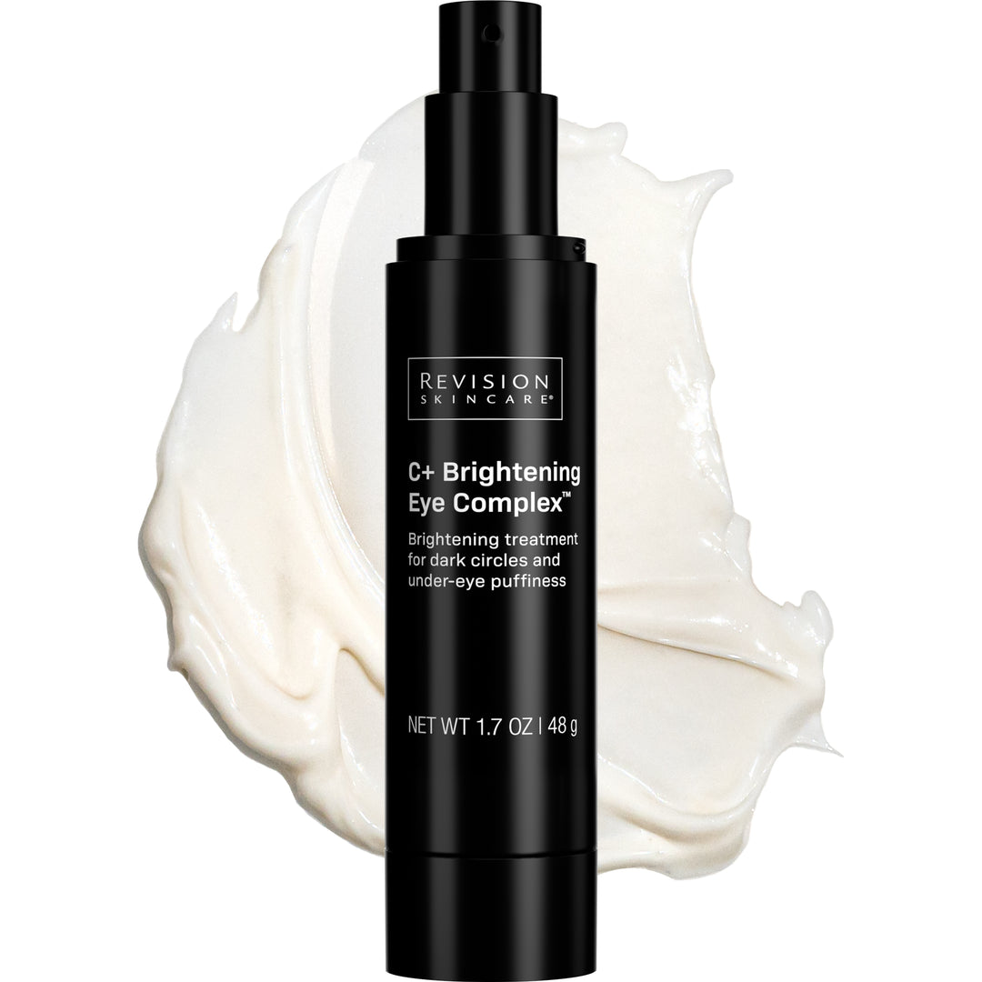 A black bottle of Revision Skincare C+ Brightening Eye Complex™ rests before a smear of white cream. Its label highlights benefits for reducing dark circles and puffiness, helping the eye area appear brighter and refreshed.