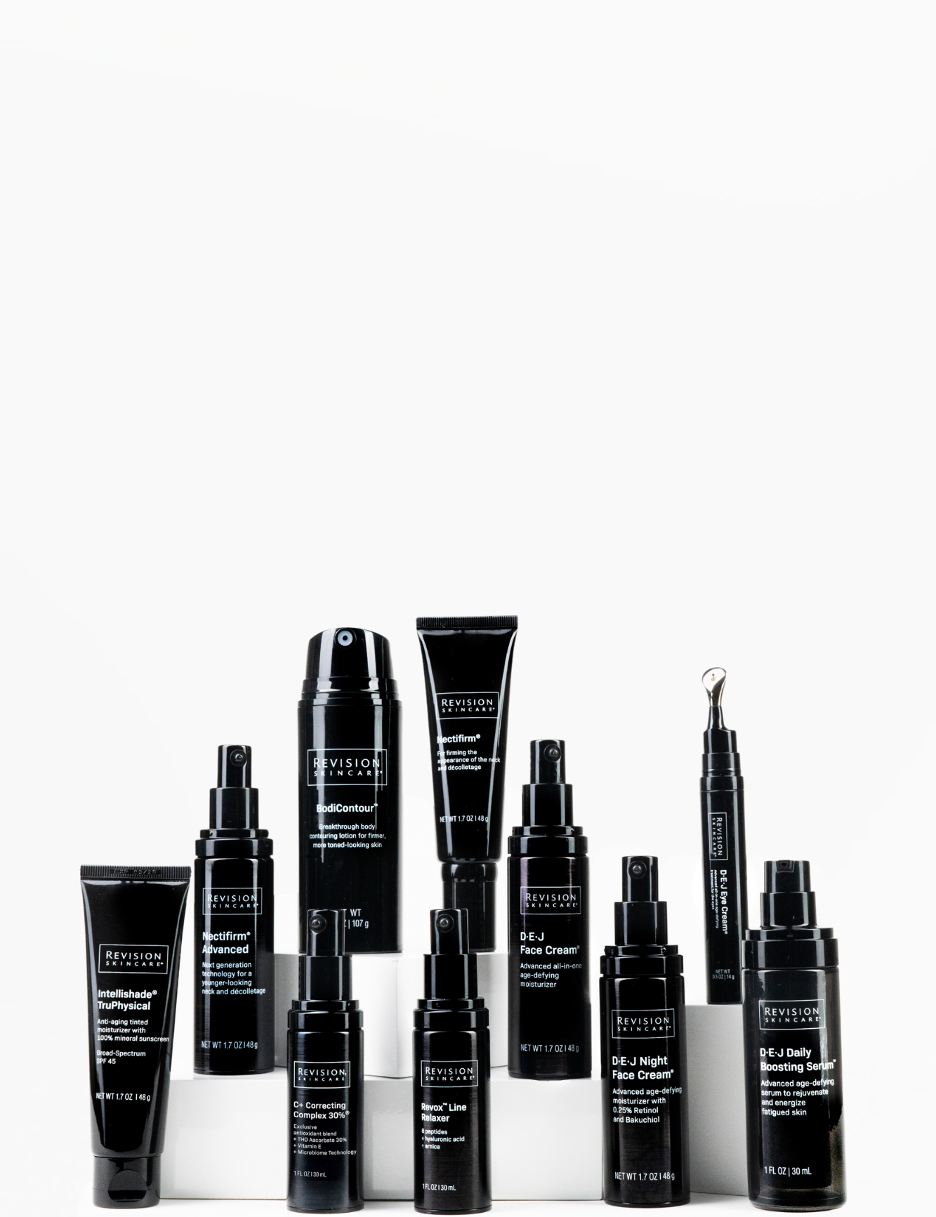 A collection of ten black bottles and tubes of Revision Skincare products arranged in rows on a white background. The containers vary in size and shape, with white text labels visible on each.