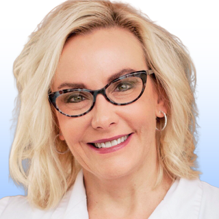 A smiling woman with blonde, shoulder-length hair wearing black cat-eye glasses, hoop earrings, and a white collared top, posed in front of a light gradient background.