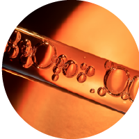 Close-up of a transparent glass dropper with droplets of amber liquid, set against a warm orange background.