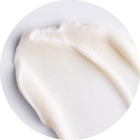A close-up view of a smooth, white creamy substance spread on a white surface, resembling a skincare cream or lotion.