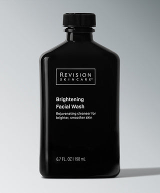 A black bottle of Revision Skincare Brightening Facial Wash with a black cap is shown against a gray background. This cleanser aims to brighten and smooth skin, featuring AHAs and BHAs, and comes in a 198 mL size.