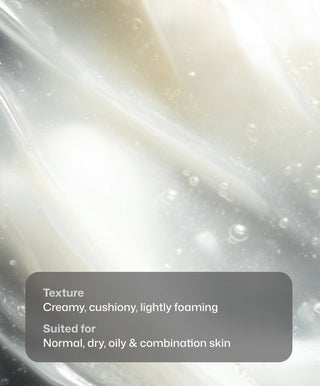 Close-up of Brightening Facial Wash by Revision Skincare shows a creamy, cushion-like, lightly foaming texture with soft white and beige swirls. Text: “Creamy, cushiony, lightly foaming. For normal, dry, oily & combination skin.” Ideal for brightening.