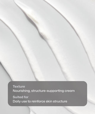 Close-up of creamy white D·E·J Face Cream® by Revision Skincare, spread in smooth, thick lines. Overlay: Texture—nourishing, structure-supporting cream for daily anti-aging use to reinforce skin structure.