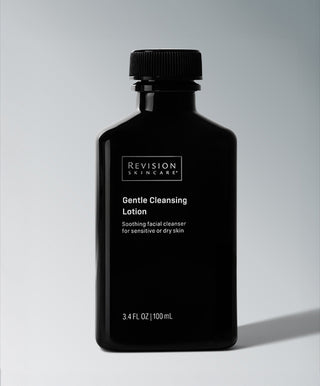A black bottle of Revision Skincare Gentle Cleansing Lotion, a 3.4 fl oz (100 mL) hydrating cleanser for sensitive or dry skin, stands on a light gray background with a soft shadow and features crisp white text.