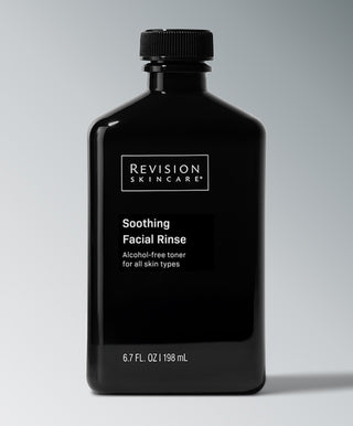 A black bottle of Revision Skincare Soothing Facial Rinse, a 6.7 fl. oz. alcohol-free toner for all skin types, is displayed against a gray background.