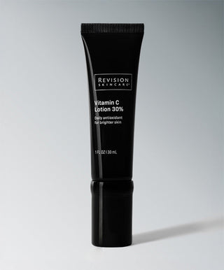 A 1 fl. oz. (30 mL) black tube of Revision Skincare Vitamin C Lotion stands upright against a light gray background. This daily antioxidant moisturizer is formulated to brighten skin with potent Vitamin C.