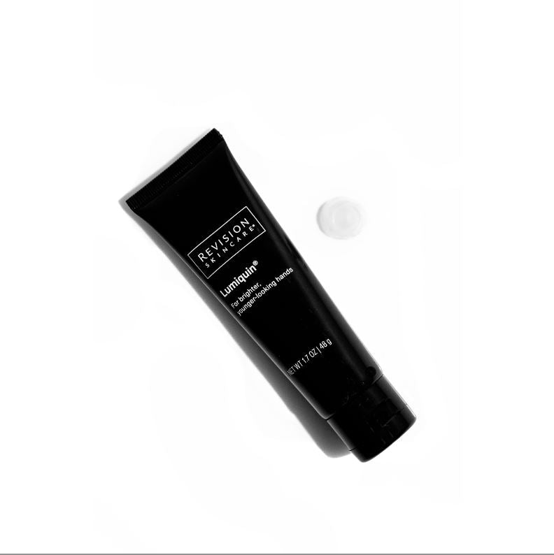 A black tube labeled Revision Skincare Lumiquin® 1.7 oz rests diagonally on a white background, beside a dab of cream—an age-defying formula by Revision Skincare that boosts moisture and nourishes dry skin.