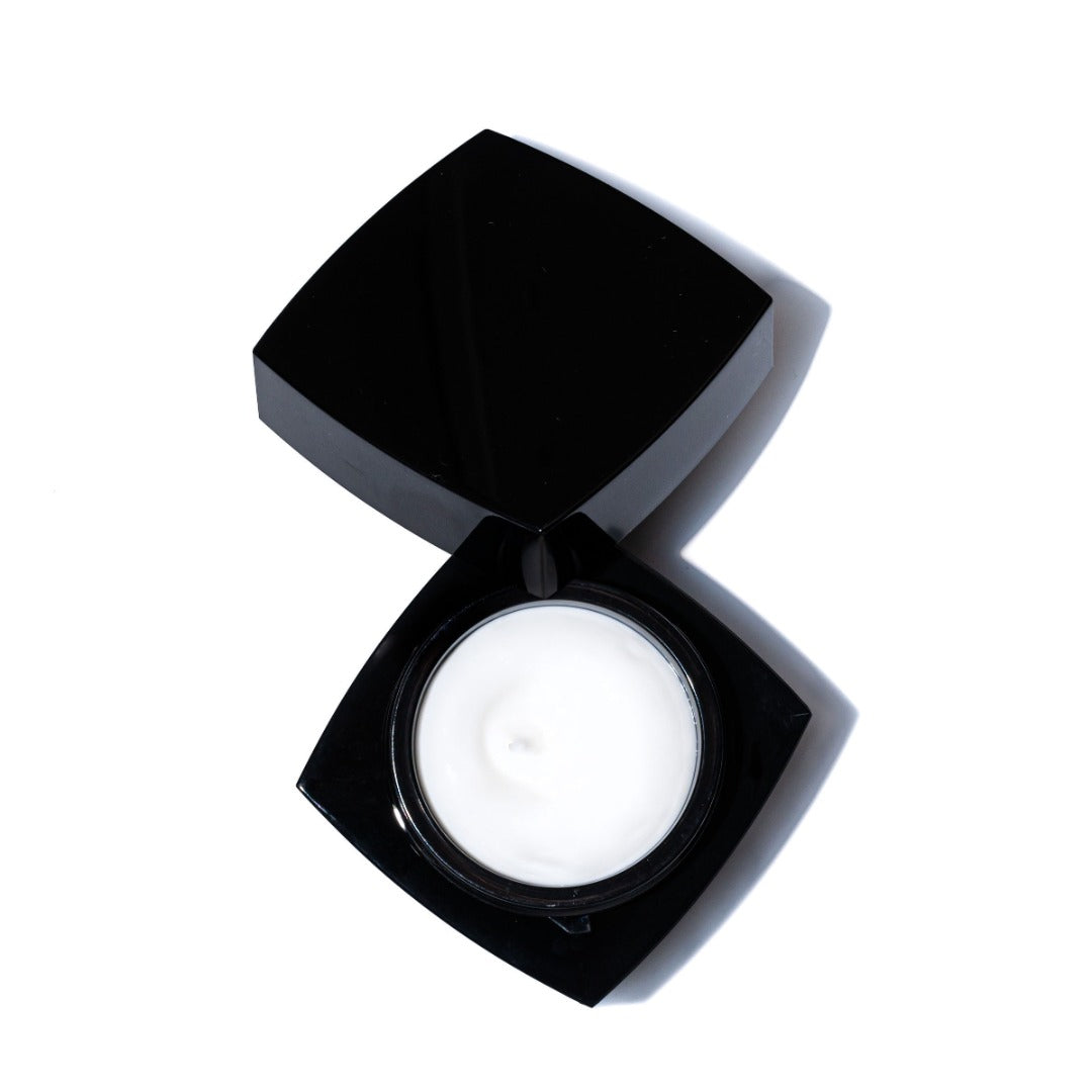 A black, square cosmetic jar with a hinged lid is open to reveal white Firming Night Treatment 1 oz cream by Revision Skincare, shown against a white background.