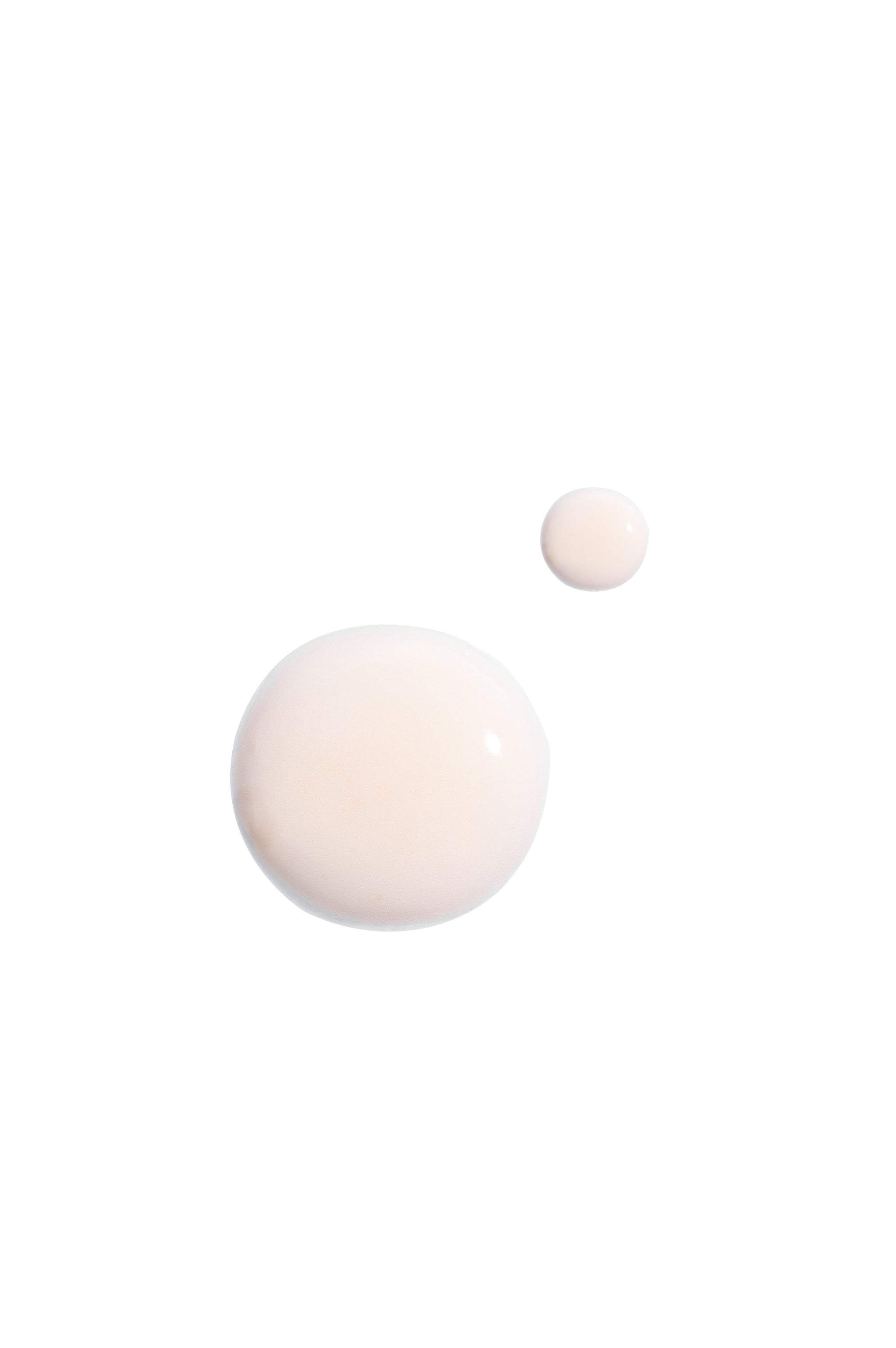 Two drops of D·E·J Daily Boosting Serum® 1oz - GWP by Revision Skincare—a creamy, light beige anti-aging serum—rest on a white background. The formula boosts skin’s cellular energy for enhanced firmness.